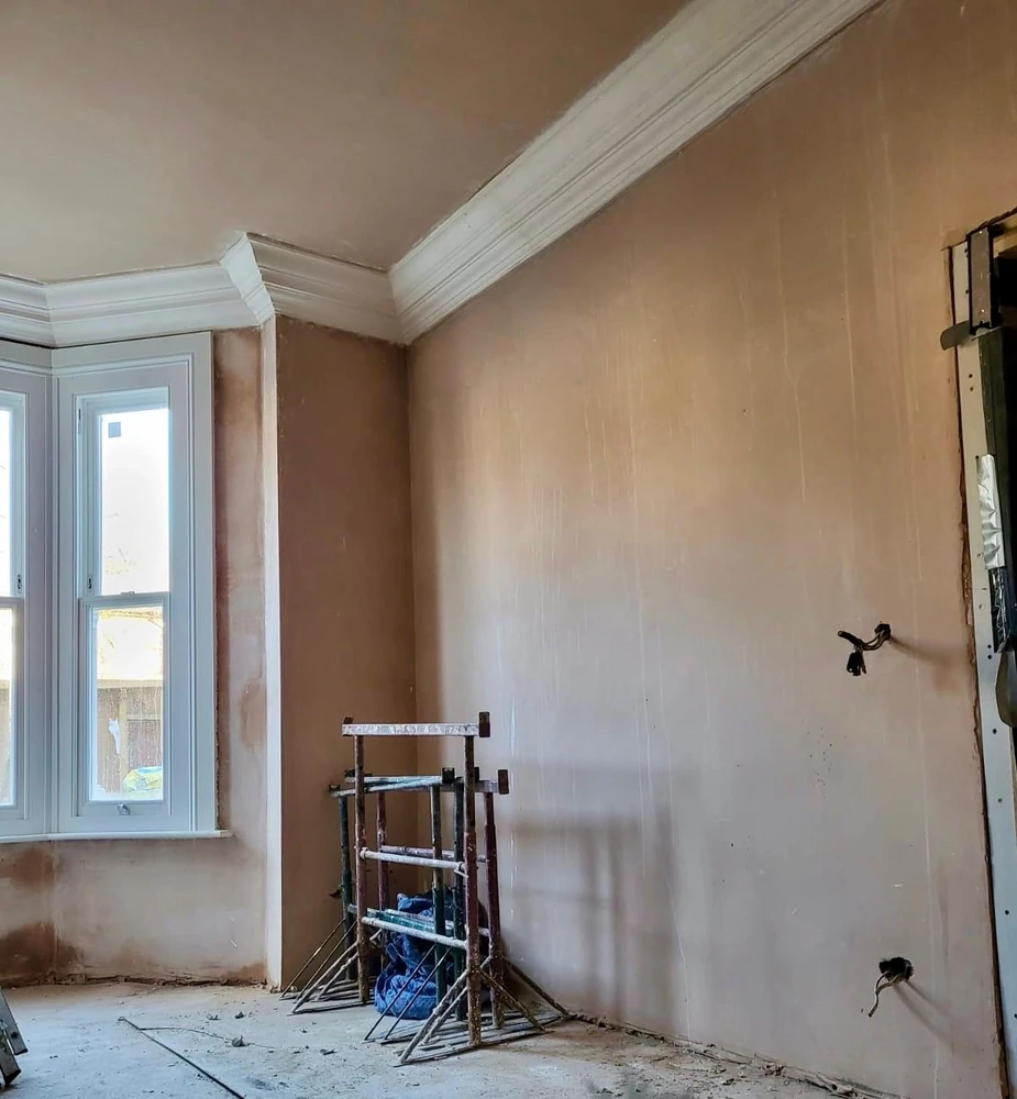 Room with fresh plaster and newly fitted coving beside a bay sash window