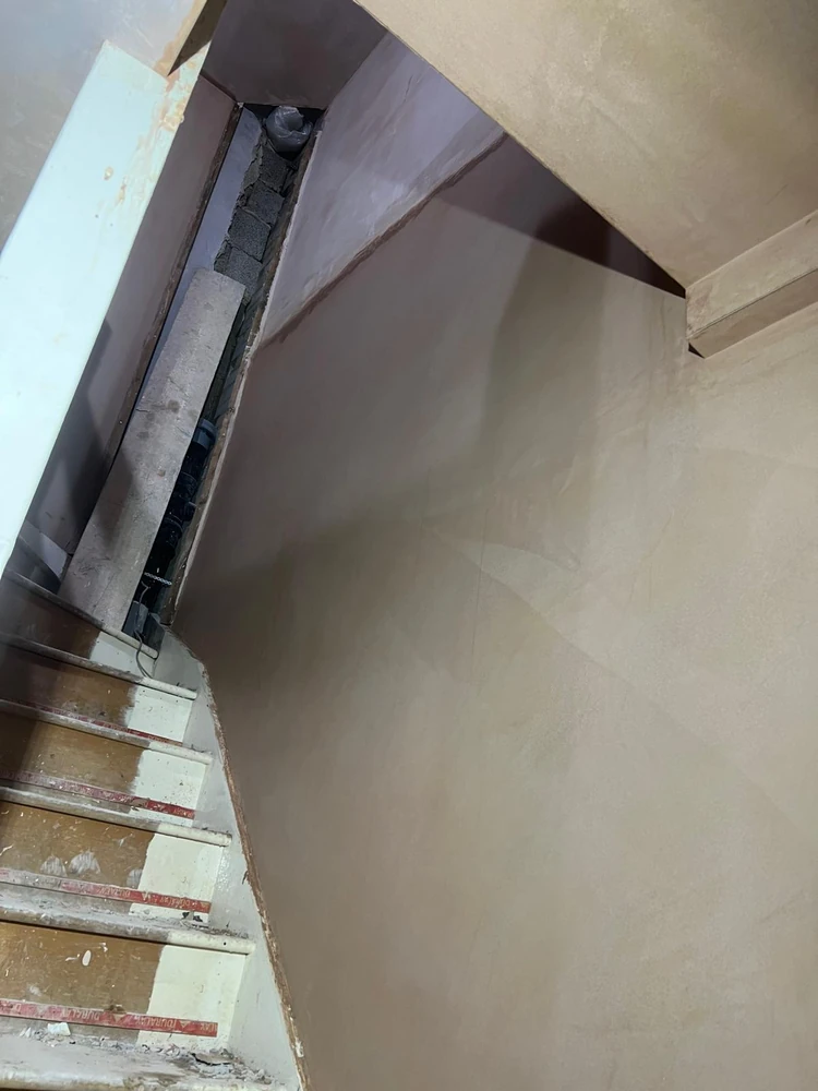 Stairwell walls freshly skimmed, trowel finish still drying
