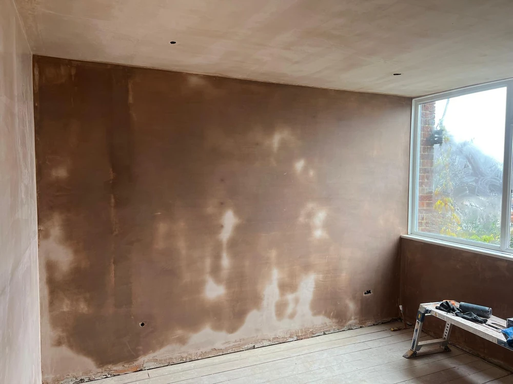 Large rear wall drying after skimming, damp patches still visible